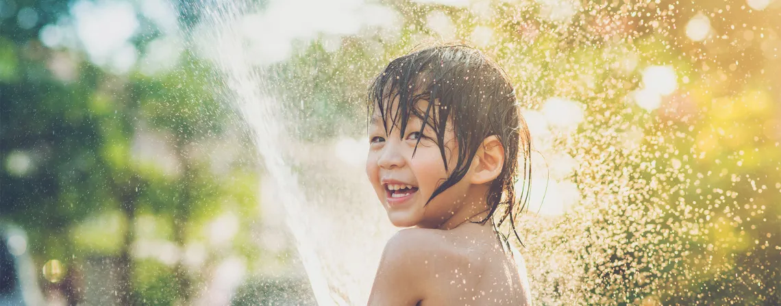 happy child playing with water in sunshine