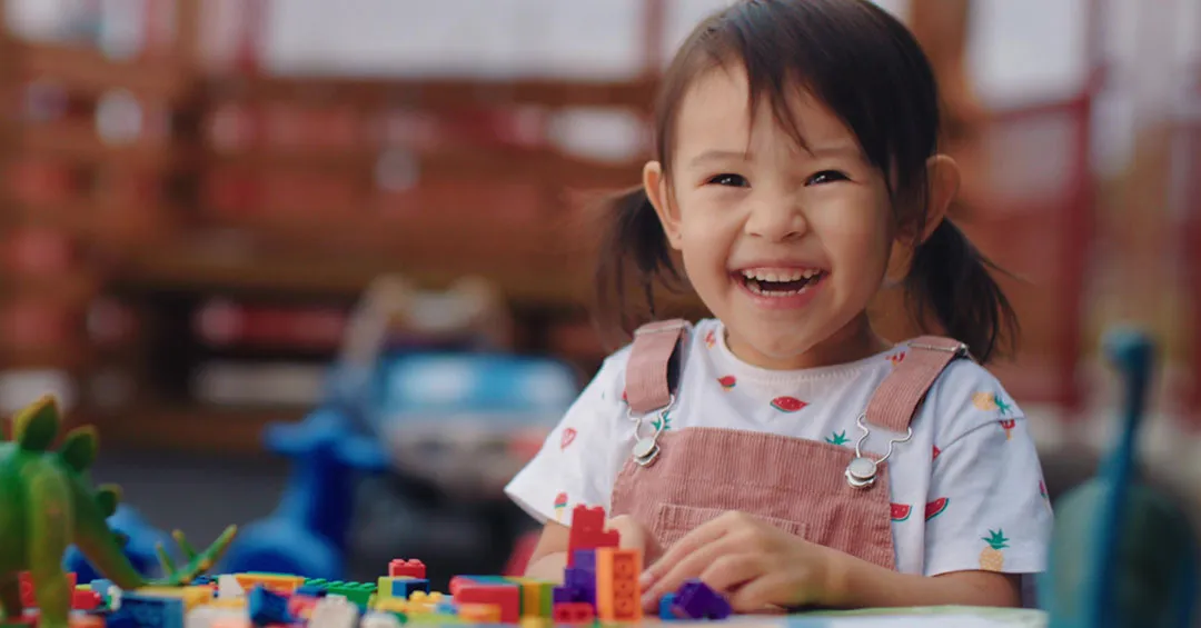 happy girl playing with LEGO bricks