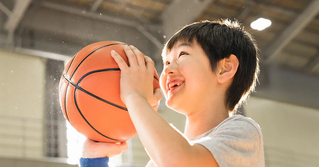 smiling boy preparing to shoot a basketball in a gymnasium