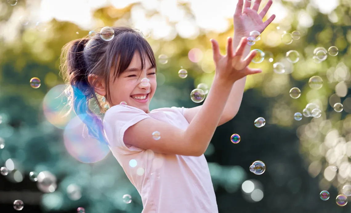 happy girl playing with bubbles outside in the sunshine