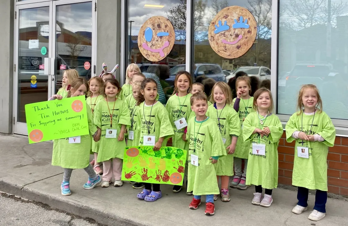 children holding thankyou signs in front of Tim Hortons