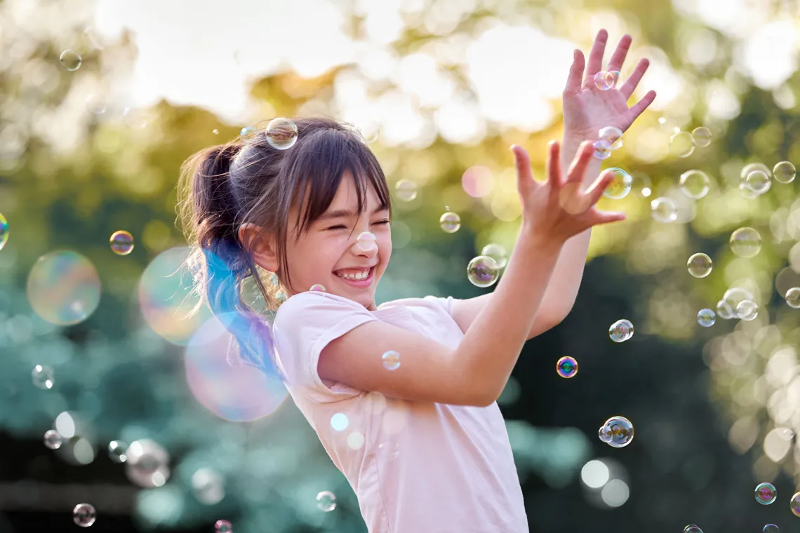 happy girl catching bubbles outside in the sunshine