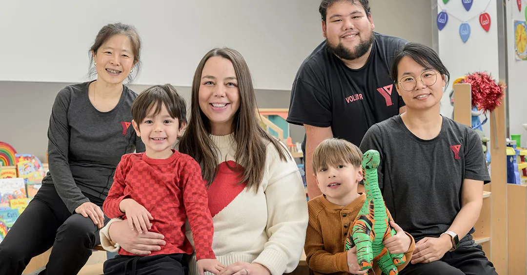 Young family and YMCA child care employees smiling at camera