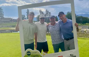 Wilson M Beck team standing behind giant photo frame on the golf course