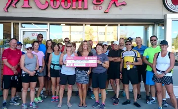 Kelowna Running Room staff holding a large check