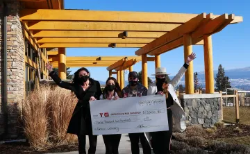 4 women outside holding a big cheque