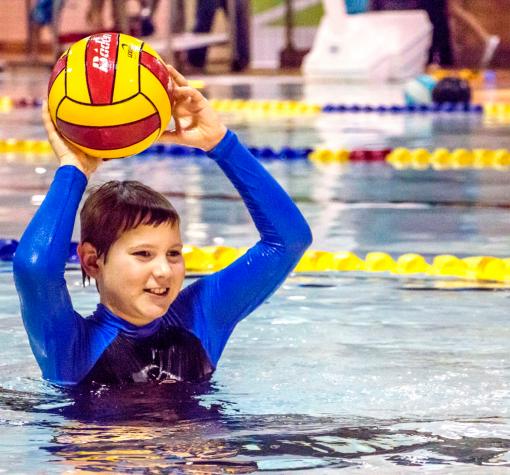 Swim lessons boy in the pool throwing a ball