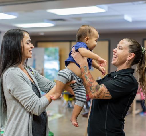 Child Minding mom passes baby to YMCA child minding staff person