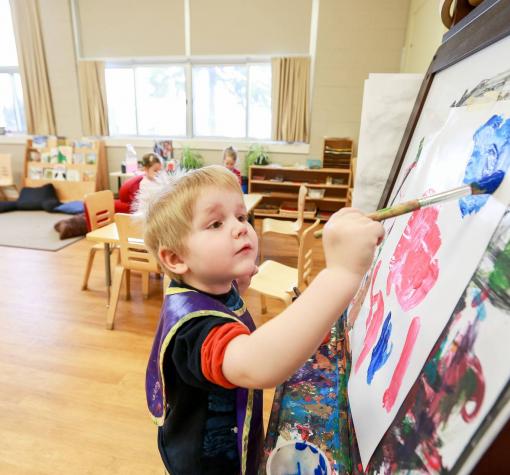 Preschool Child painting with brush and easel