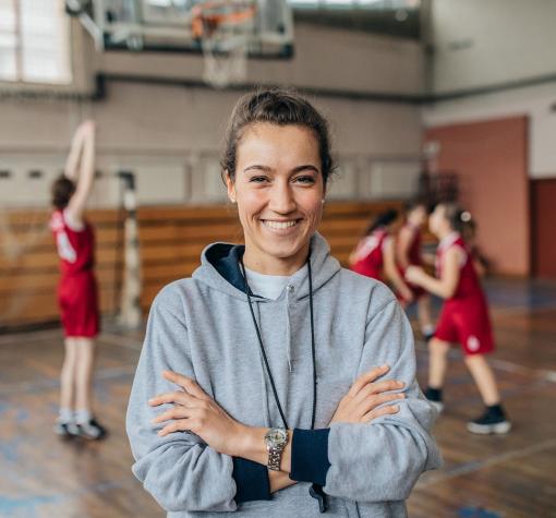 volunteer - mentor basketball coach in gymnasium with team playing behind