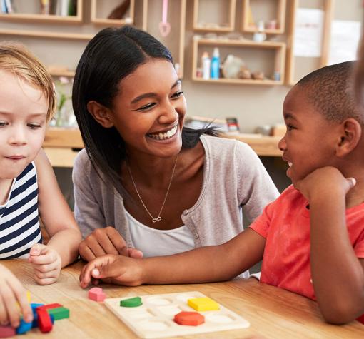 child care worker helping children with shape puzzle