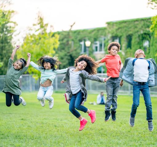 group of children jumping in a grassy field