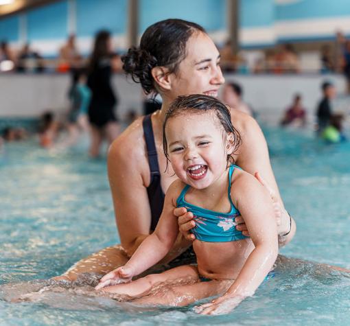 mother and young child having fun in a shallow pool area